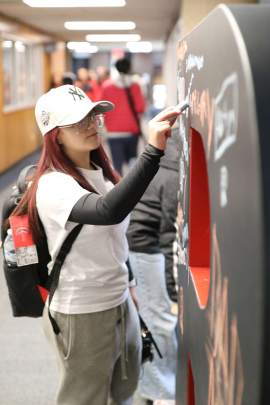 Nottingham High School student Anahi Arteaga, 15, writes with chalk on a giant R in the College Avenue Student Center during Rutgers Day 2026.