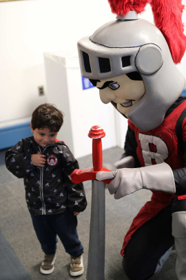 Dominic Rodriguez, 3, of Milltown, N.J., shyly poses with Sir Henry inside the College Avenue Student Center during Rutgers Day 2026.