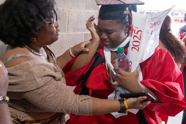 A graduating student crying and being consoled by a family member