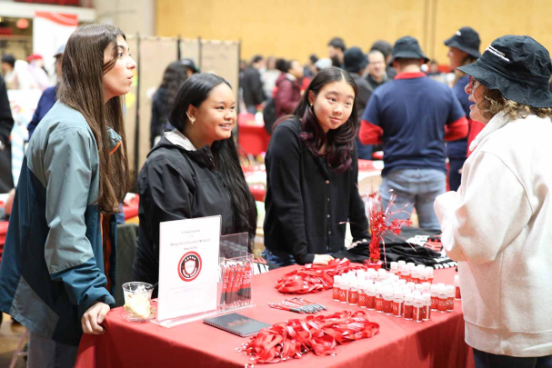 Undergraduate students Isabella Esposito (left), Mariella Garcia and Alex Lee chat with a visitor at the Rutgers University Student Assembly table in the College Avenue Gymnasium on Saturday.